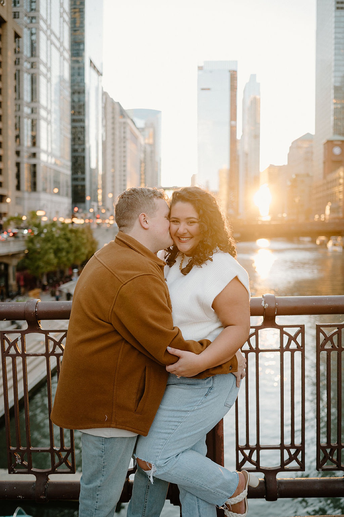 couple kiss on a bridge over river during classy outdoor shoot by Chicago wedding photographer