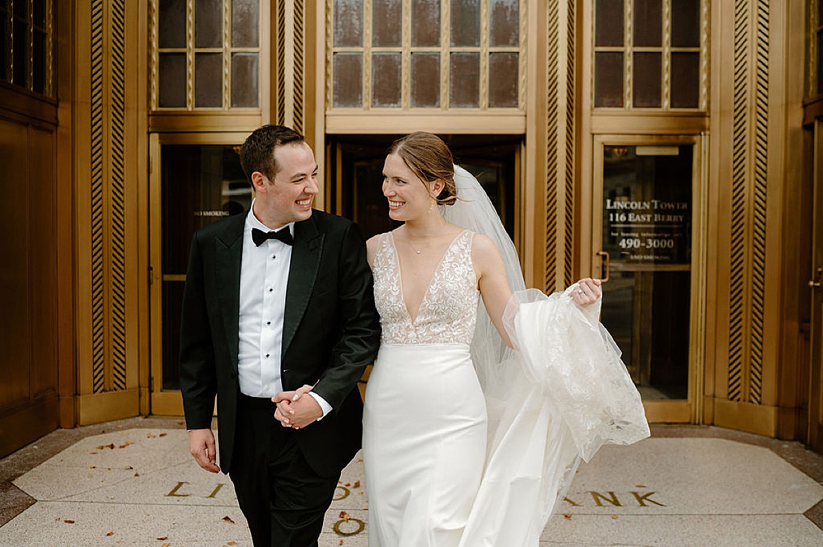 newlywed husband and wife pose in front of bank building after Idyllic Fort Wayne country club wedding