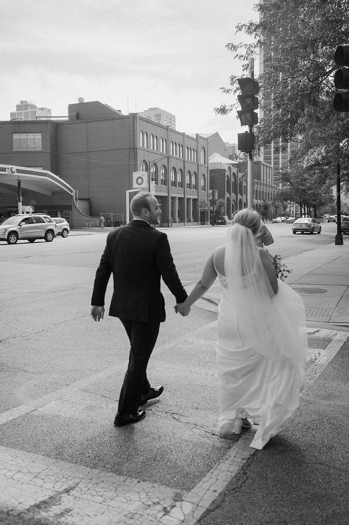 newlywed bride and groom cross the street holding hands after intimate Chicago ceremony