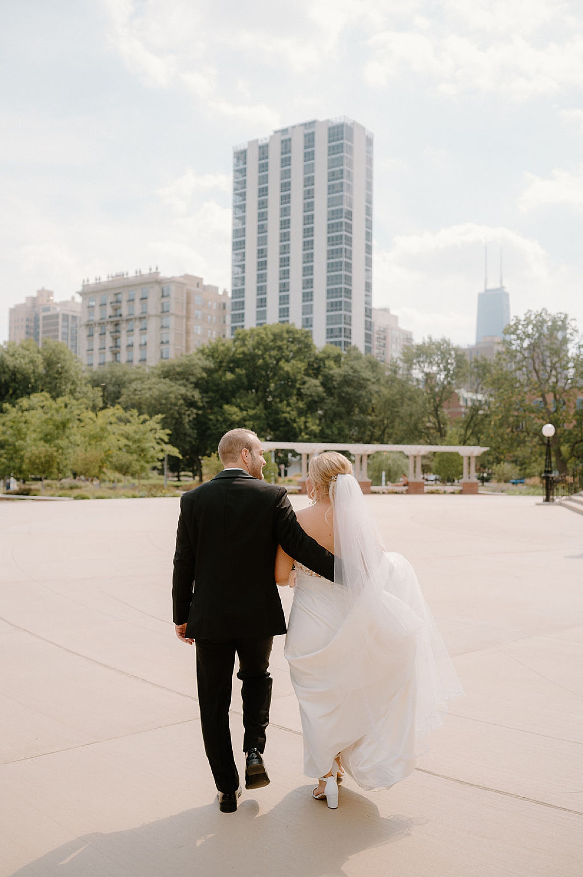newlywed bride and groom walk through city park after wedding ceremony shot by Indigo Lace Collective