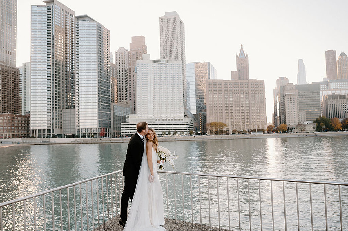 bride and groom pose overlooking the water in Chicago after elegant ceremony at the clark