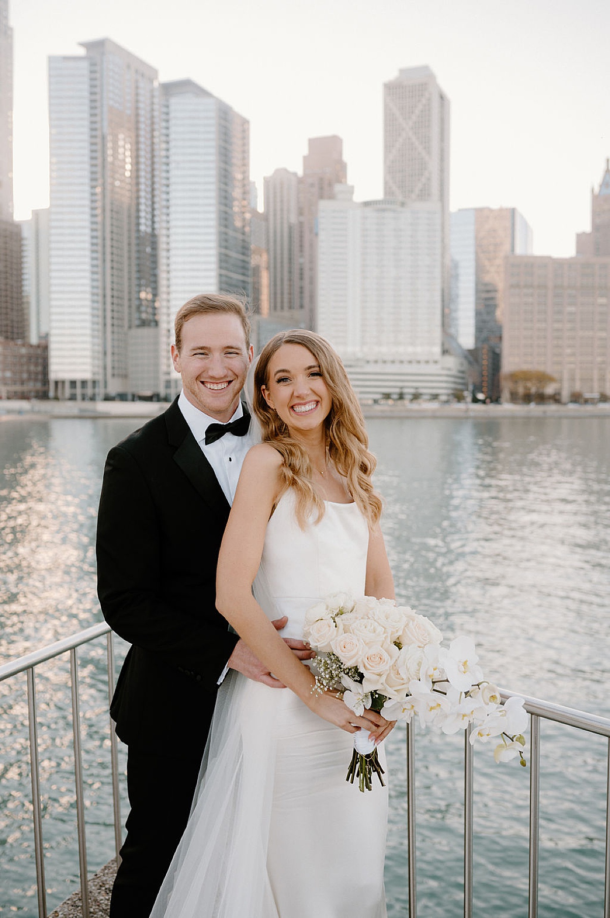 handsome bride and groom in pose overlooking the river in Chicago after elegant ceremony at the clark