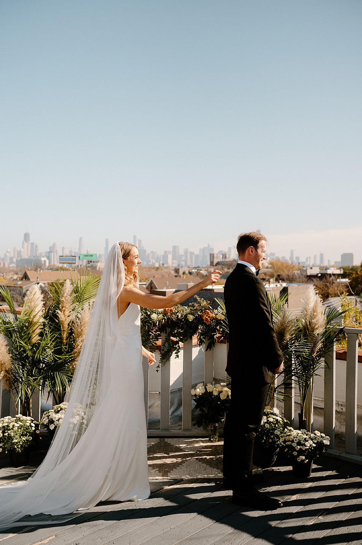 bride taps groom on the shoulder on rooftop for first look before elegant ceremony at the clark