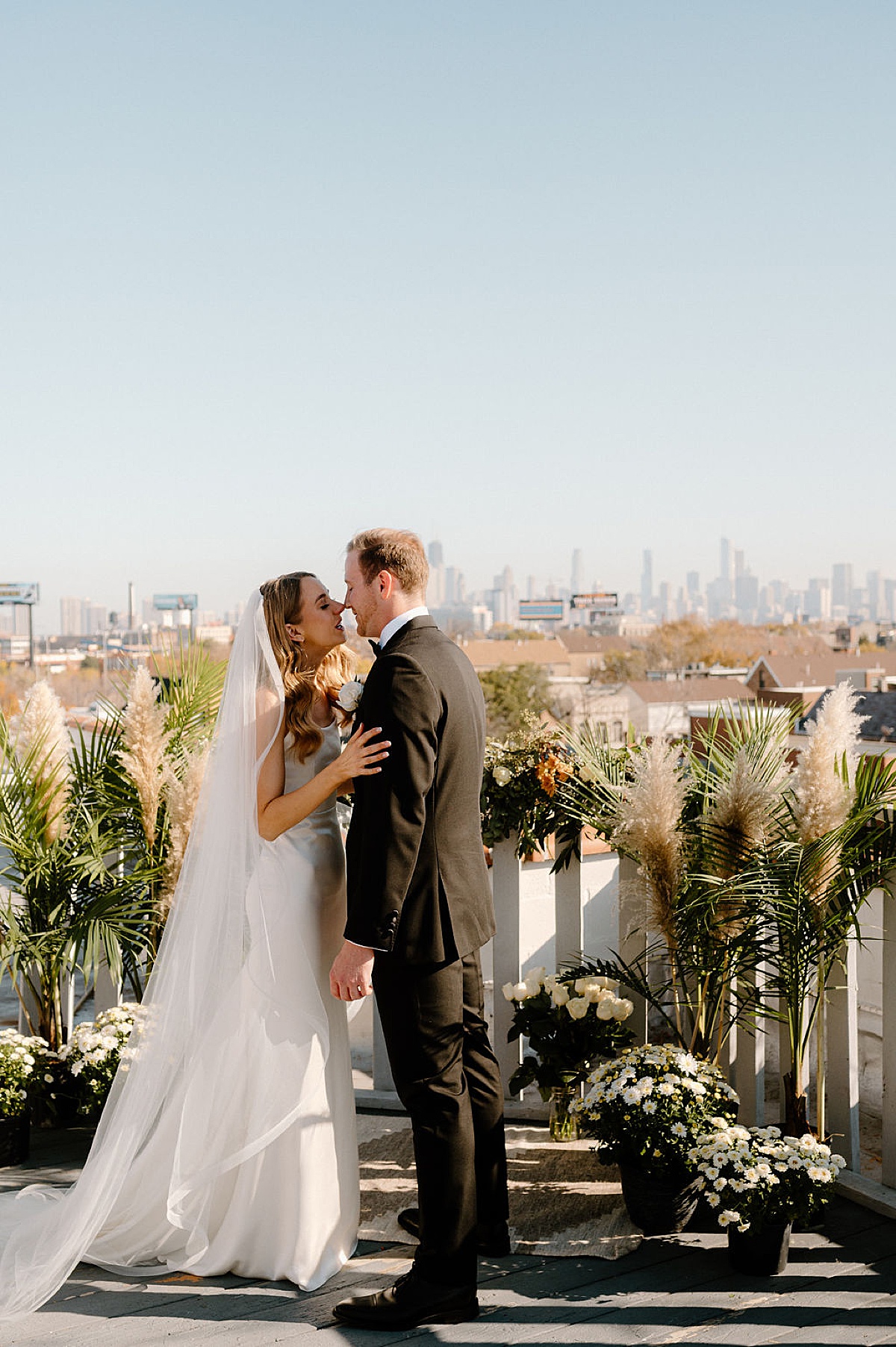 bride and groom kiss on chicago rooftop before elegant ceremony at the clark
