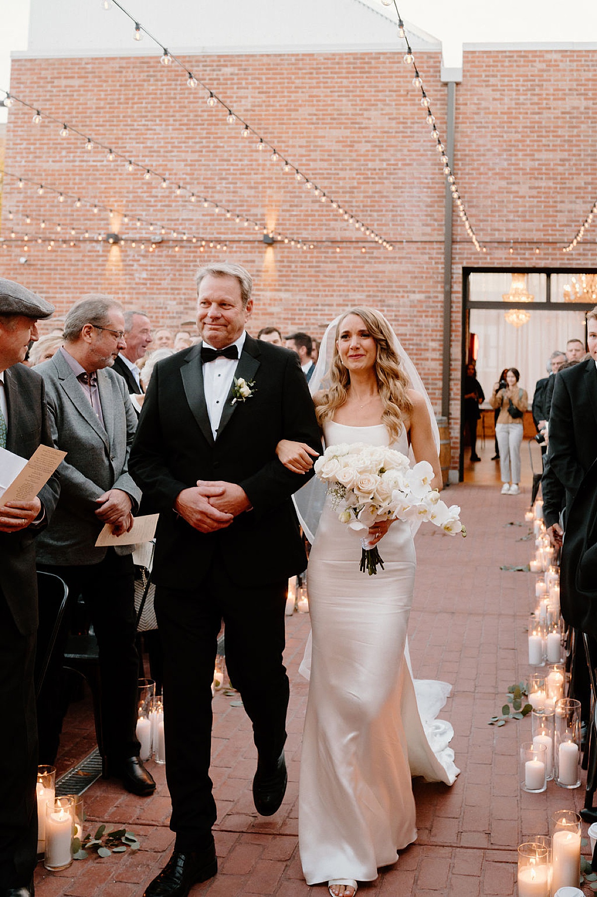 bride walks down the aisle with her father during candlelit ceremony shot by Indigo Lace Collective