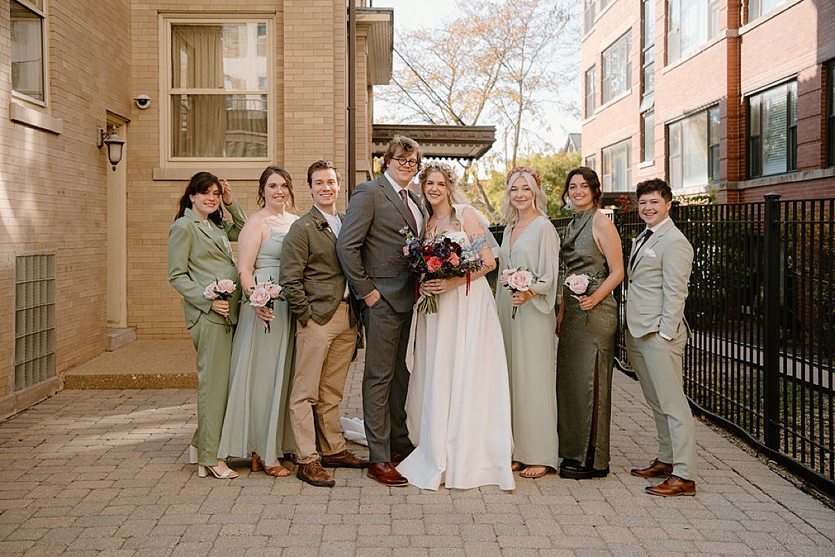Bride and groom pose with wedding party in shades of green before elegant celebration at Frank Lloyd Wright house