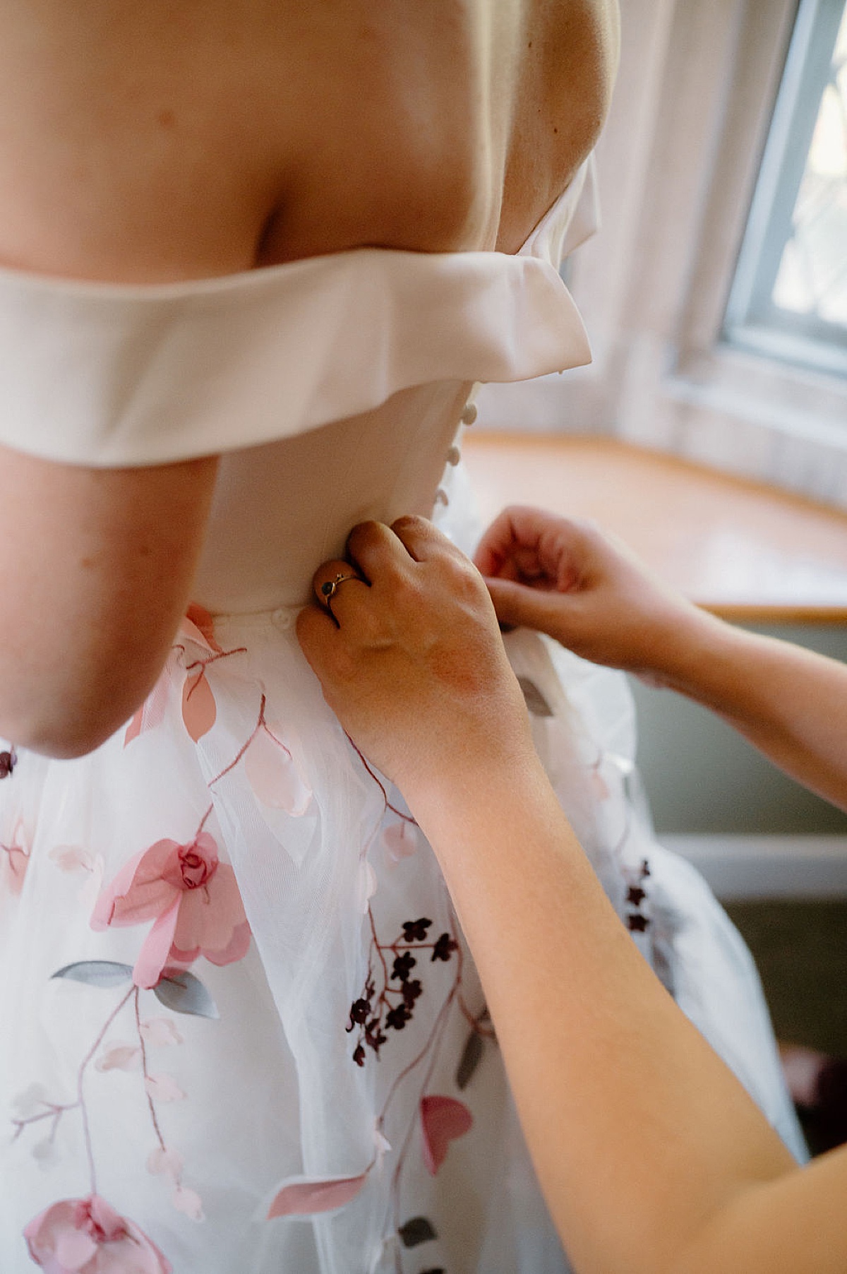 bridesmaid helps fasten bride's gown before romantic autumn arboretum wedding