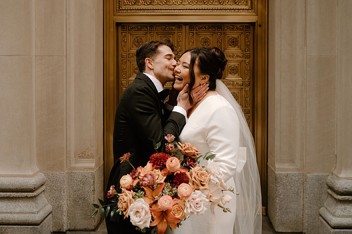 bride and groom kiss in front of iconic Chicago gold doors before Autumn Fairlie Wedding