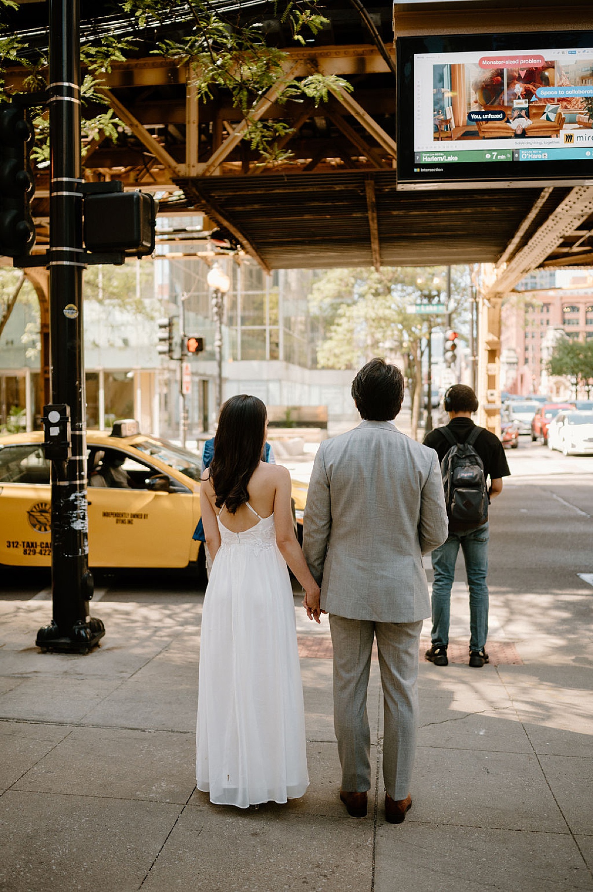 cute bride and groom hold hands under the L train bridge in Chicago after city hall sweetheart elopement