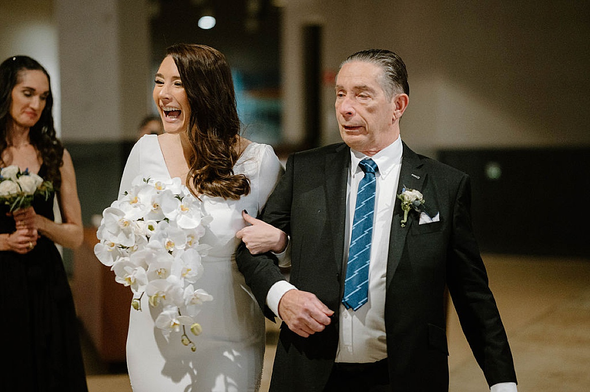 bride with elegant orchid bouquet walks the aisle with her father before ceremony shot by Chicago wedding photographer