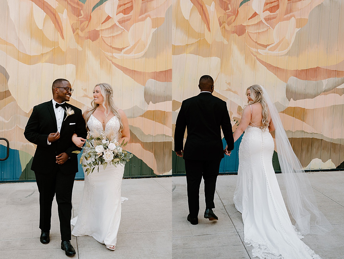 bride in lace gown and boho bouquet poses with dapper groom in front of street mural shot by Indigo Lace Collective