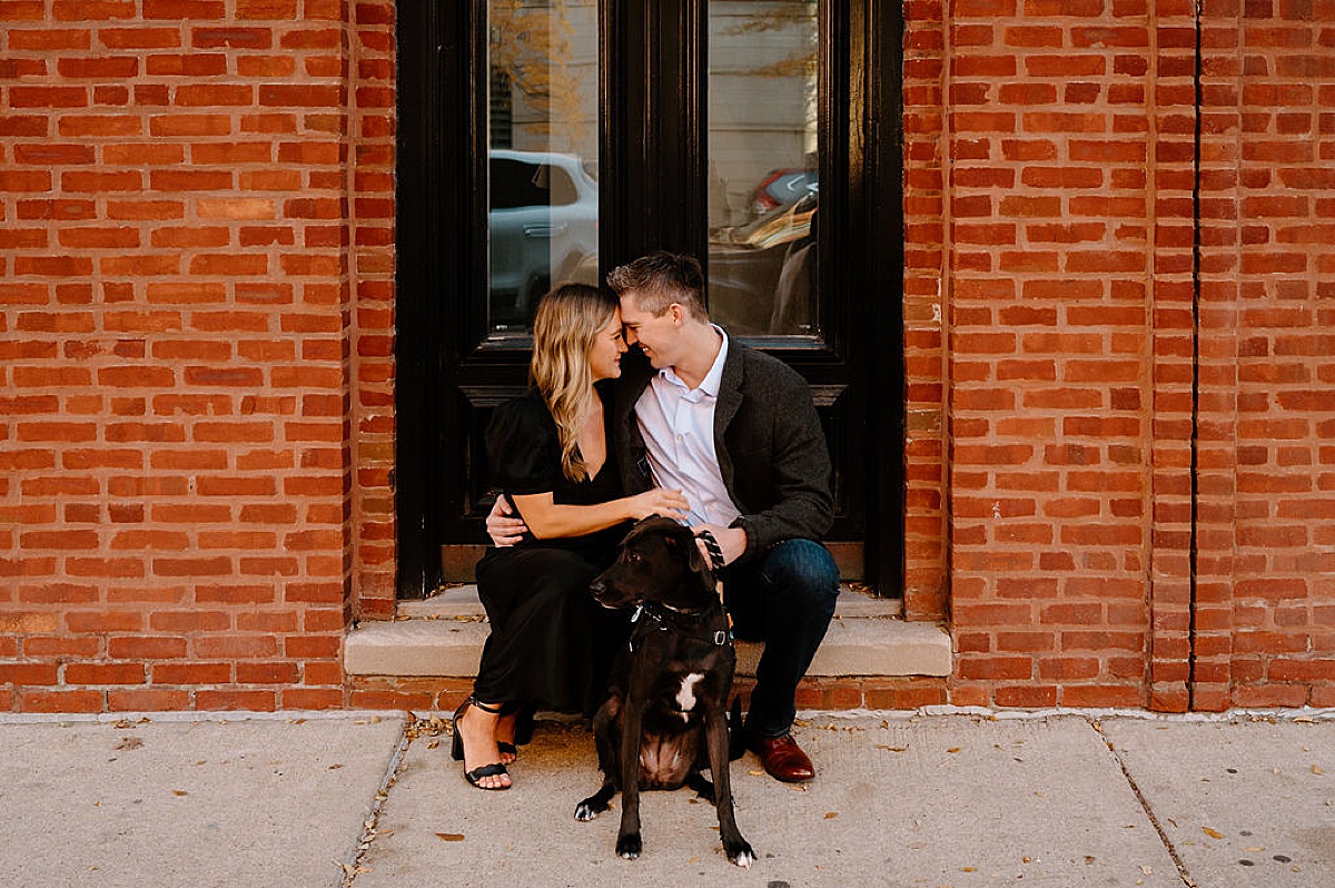 loving couple pose with their dog during urban puppy love engagement session
