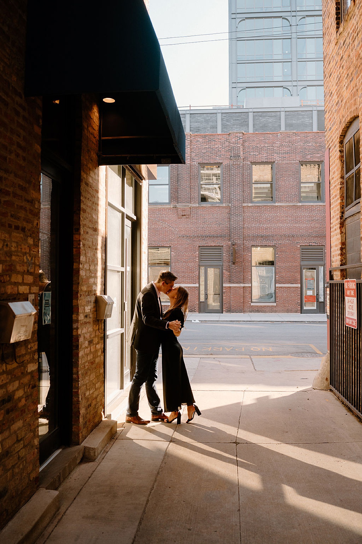 young professional couple kiss in alleyway during puppy love engagement session