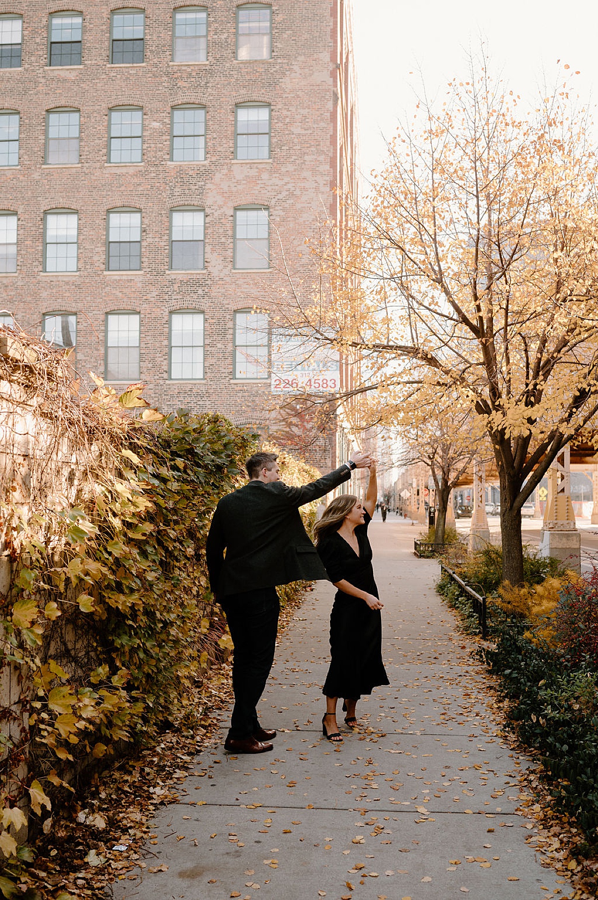 fiance twirls his bride-to-be on leafy path during puppy love engagement session