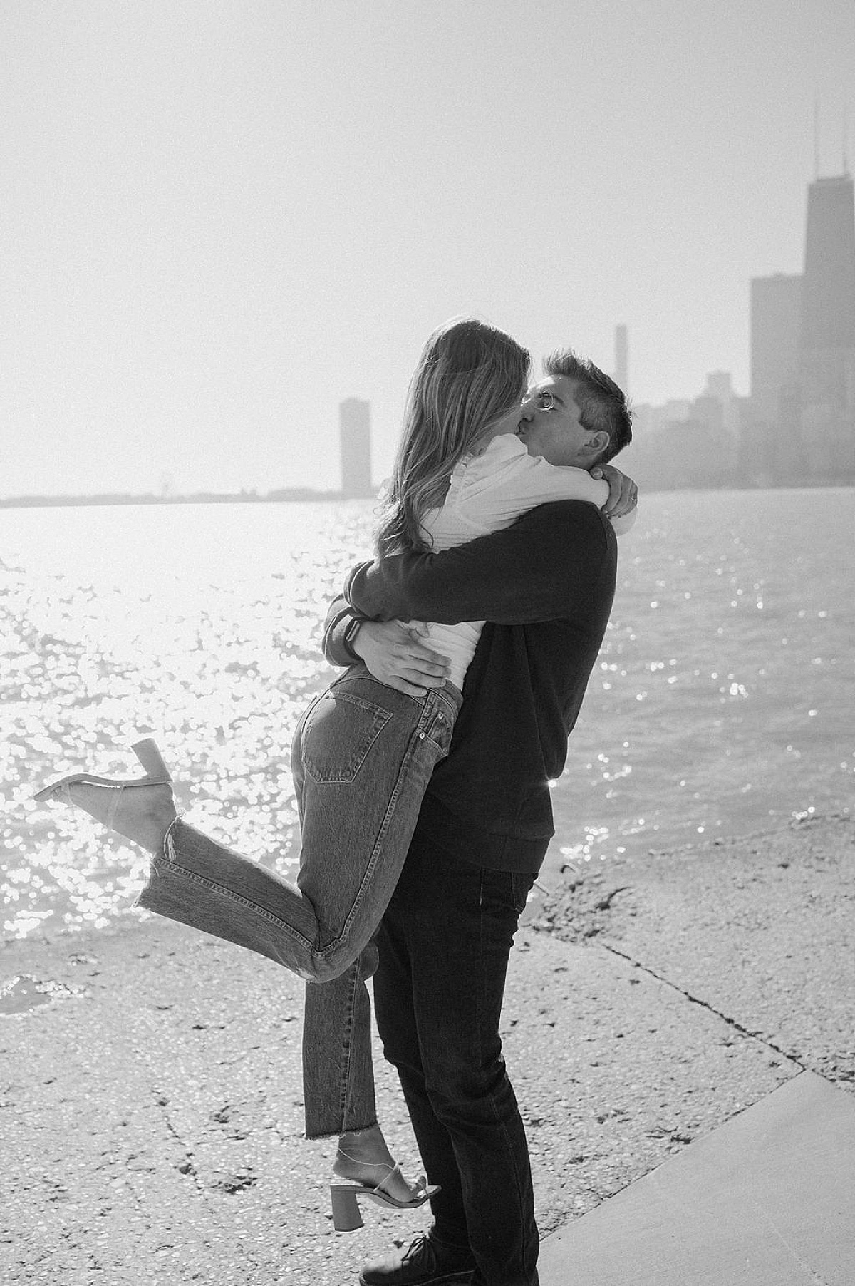 engaged couple kiss at waterfront with Chicago skyline during shoot with Indigo Lace Collective