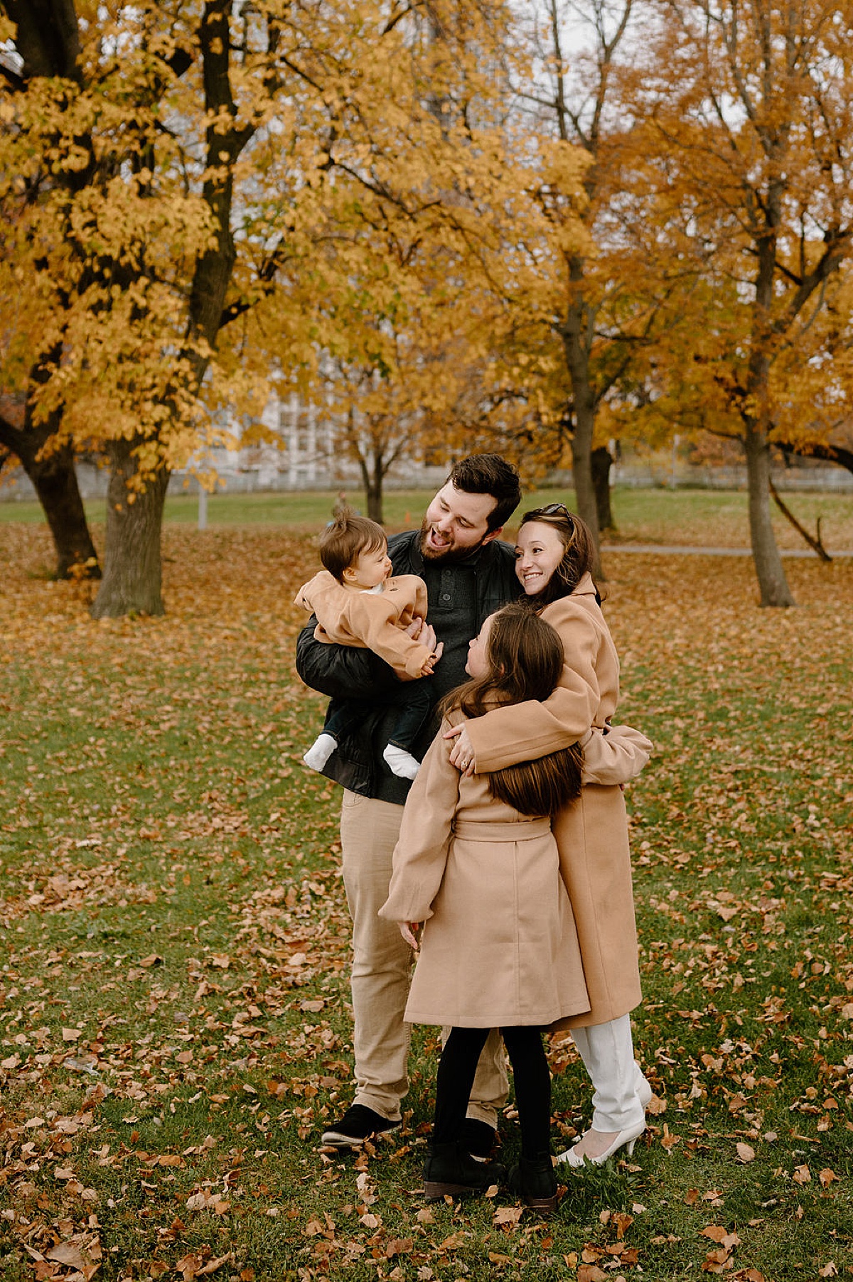 cute family with two kids pose in fall leaves during North Ave Beach Family Session