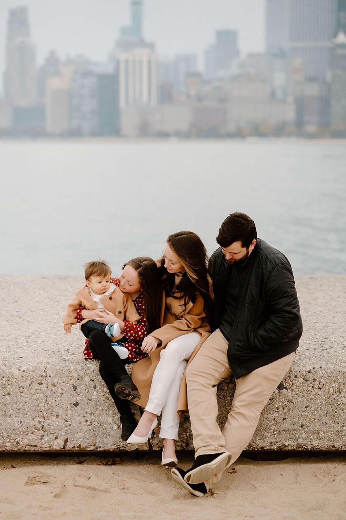 cute family in classy fall outfits sit on a bench during North Ave Beach Family Session
