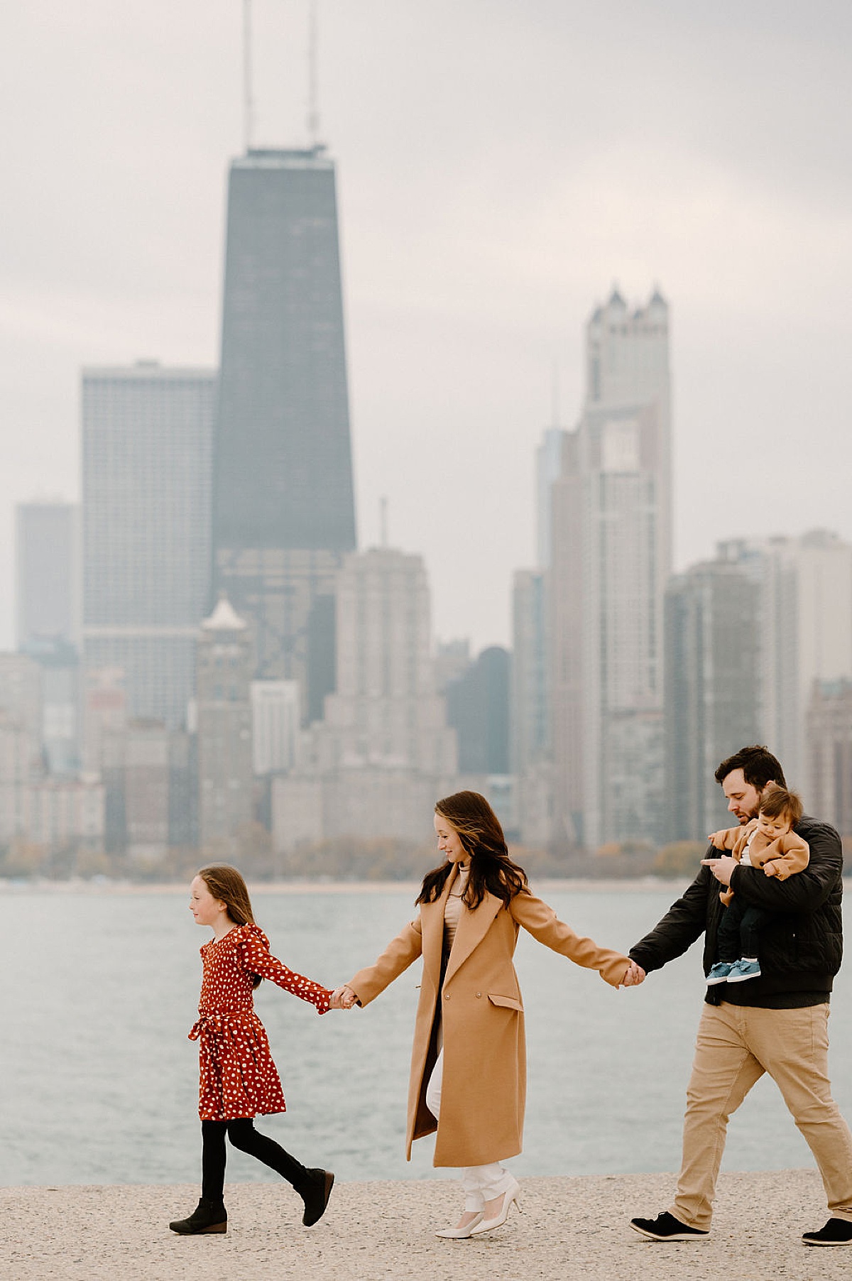 family of four walks hand in hand next to Chicago waterfront during photoshoot with Indigo Lace Collective