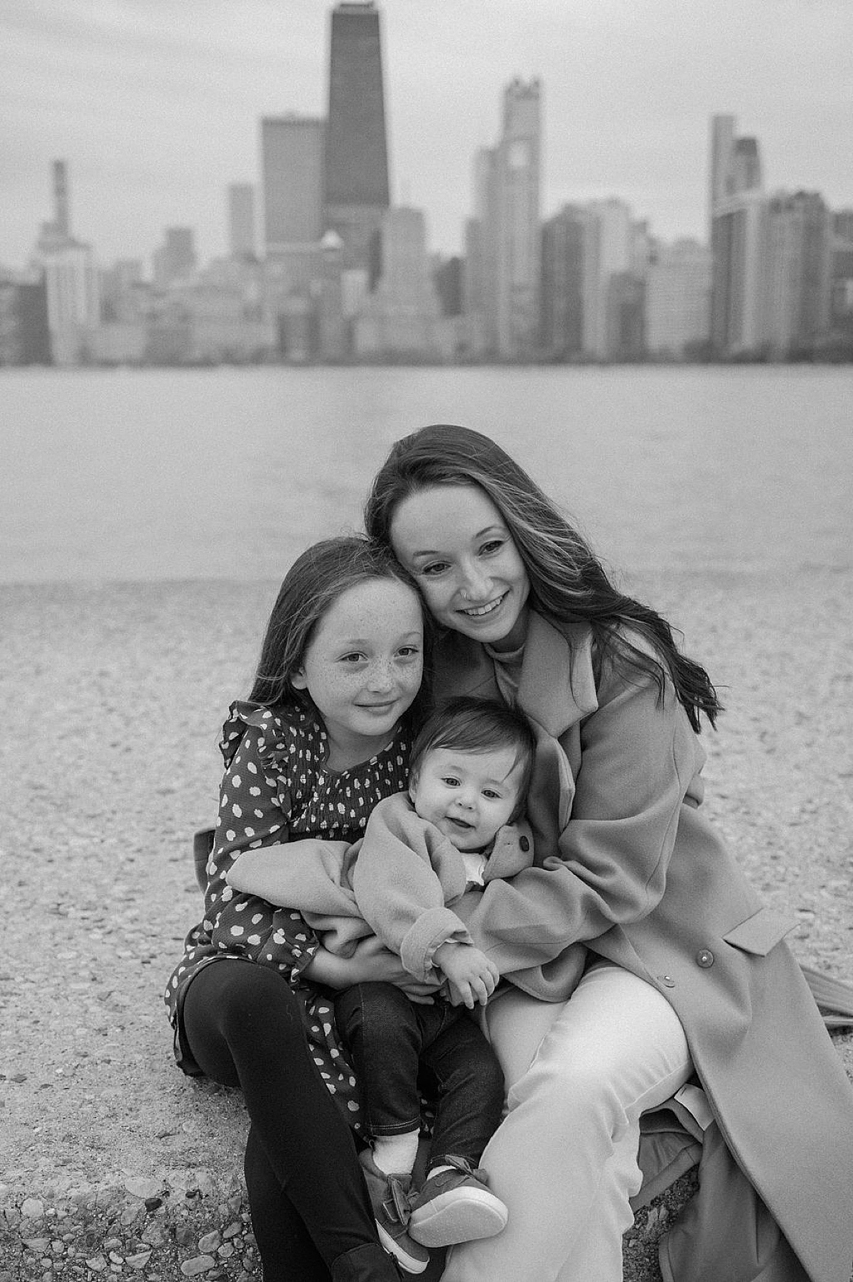 mom and two little daughters hug during fall photos taken by Chicago family photographer