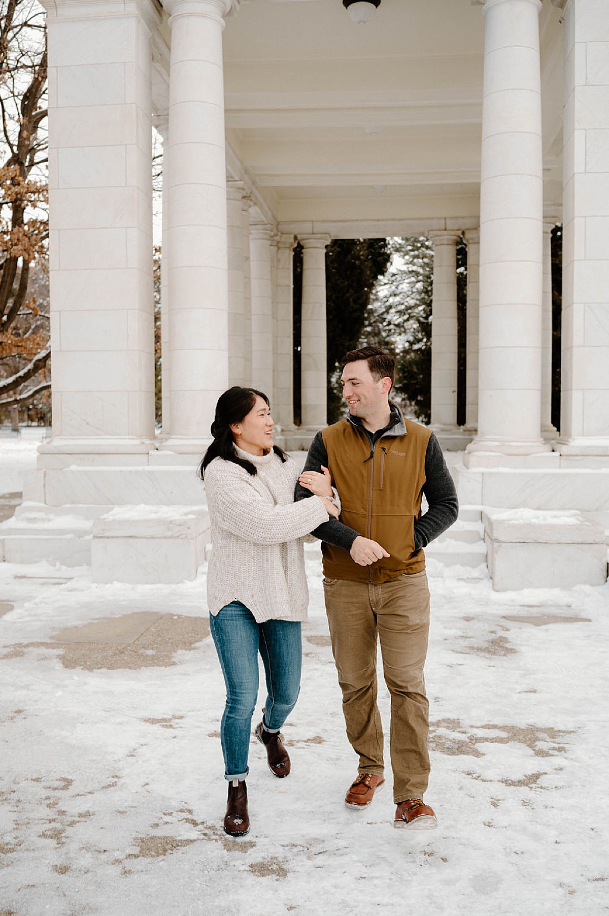 cute Colorado couple walk arm in arm during snowy Cheesman Park engagement session