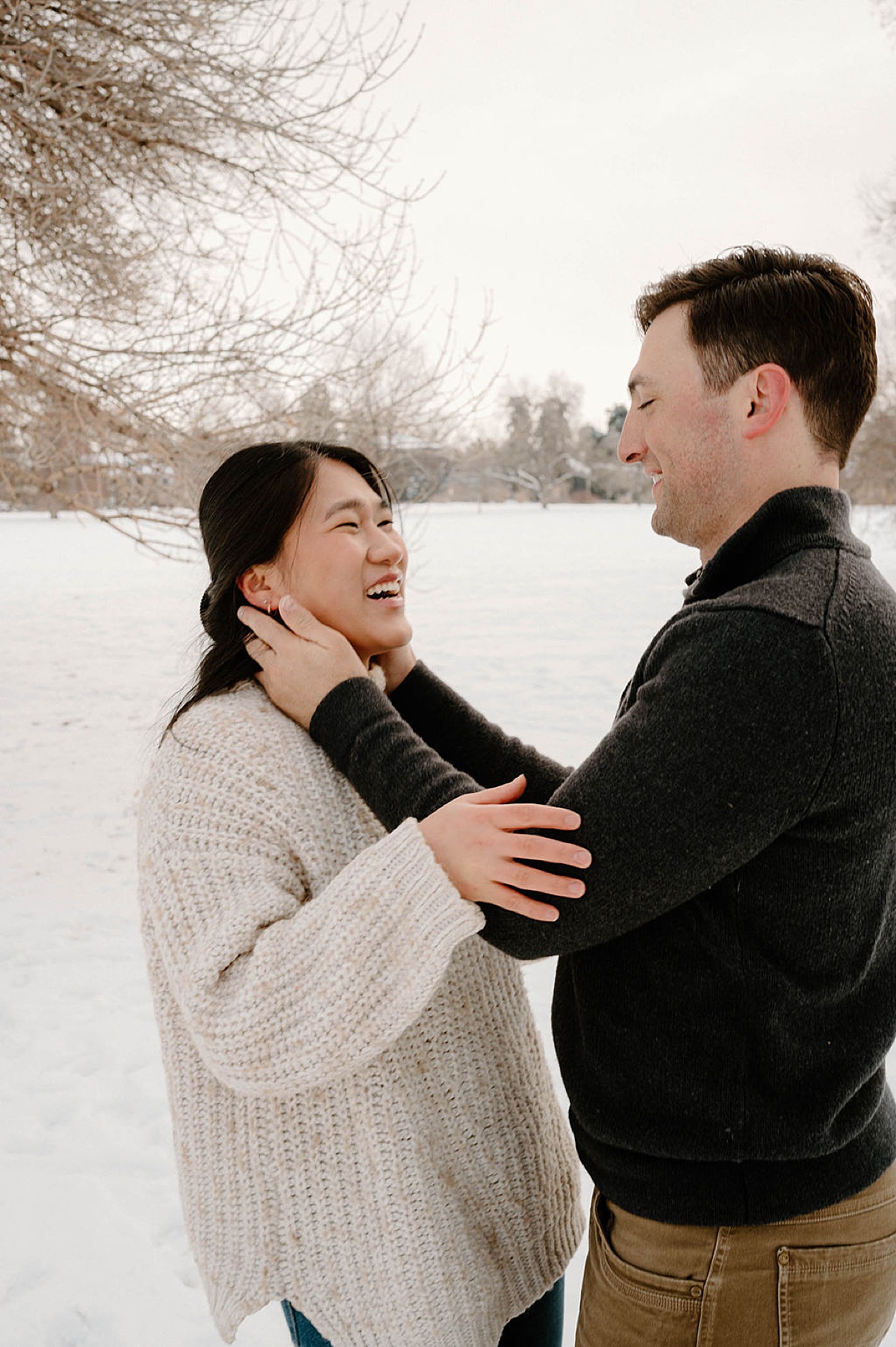 cute couple embraces during snowy Colorado engagement shoot by Indigo Lace Collective