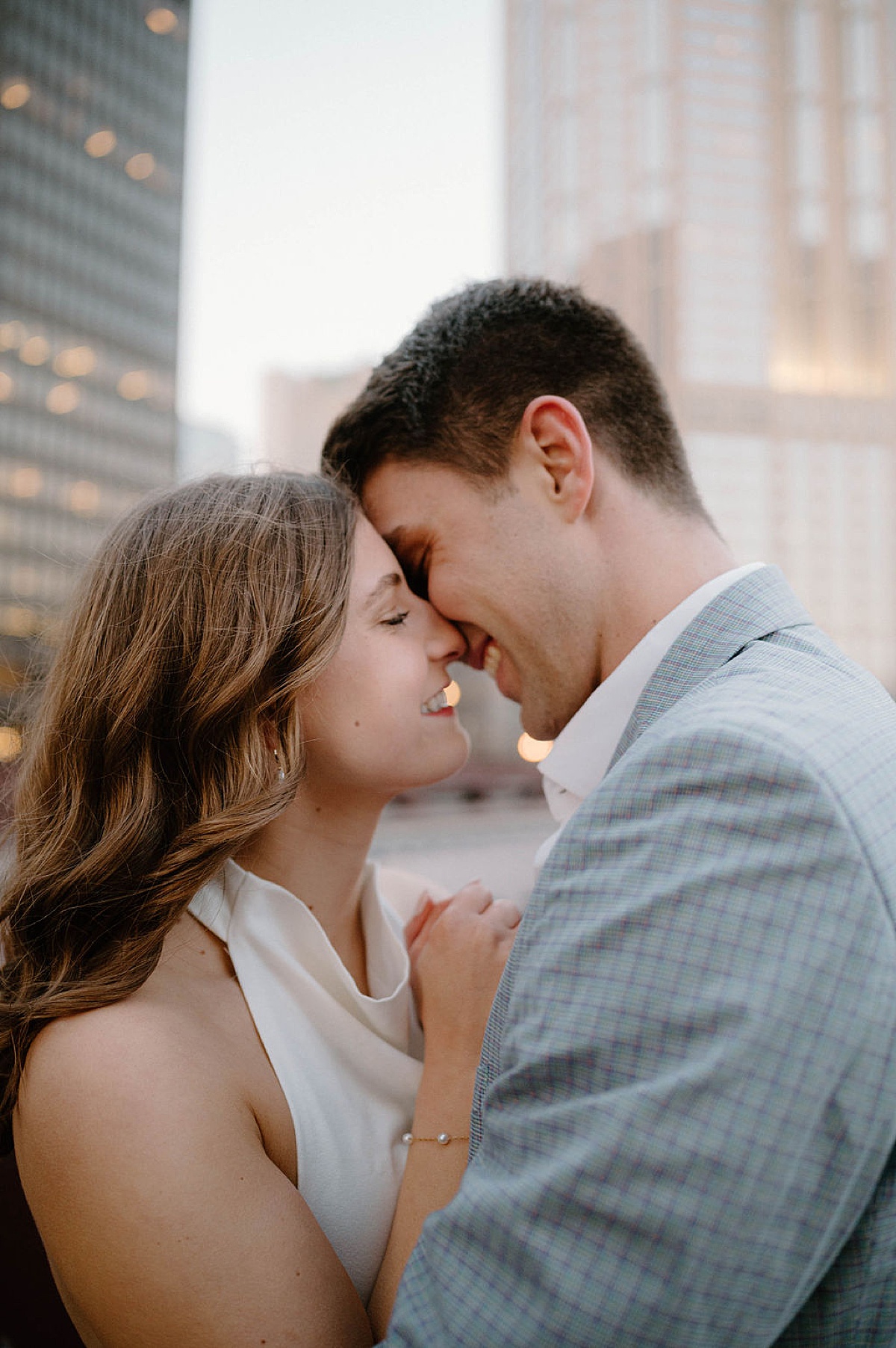cute couple kiss with twinkling lights of the city during chic post office engagement session 