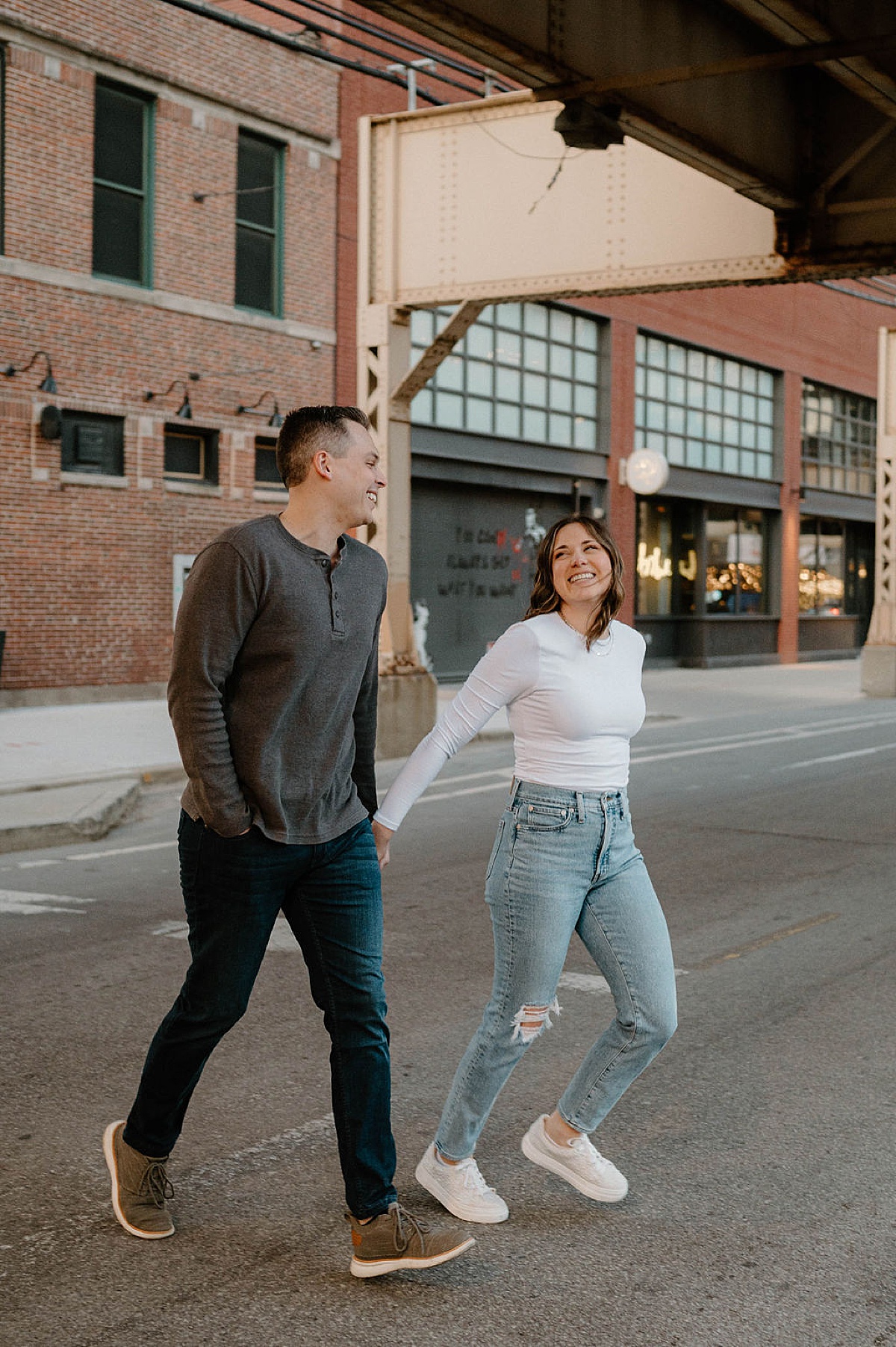 newly engaged couple hold hands in Chicago crosswalk during sweet photoshoot with Indigo Lace Collective