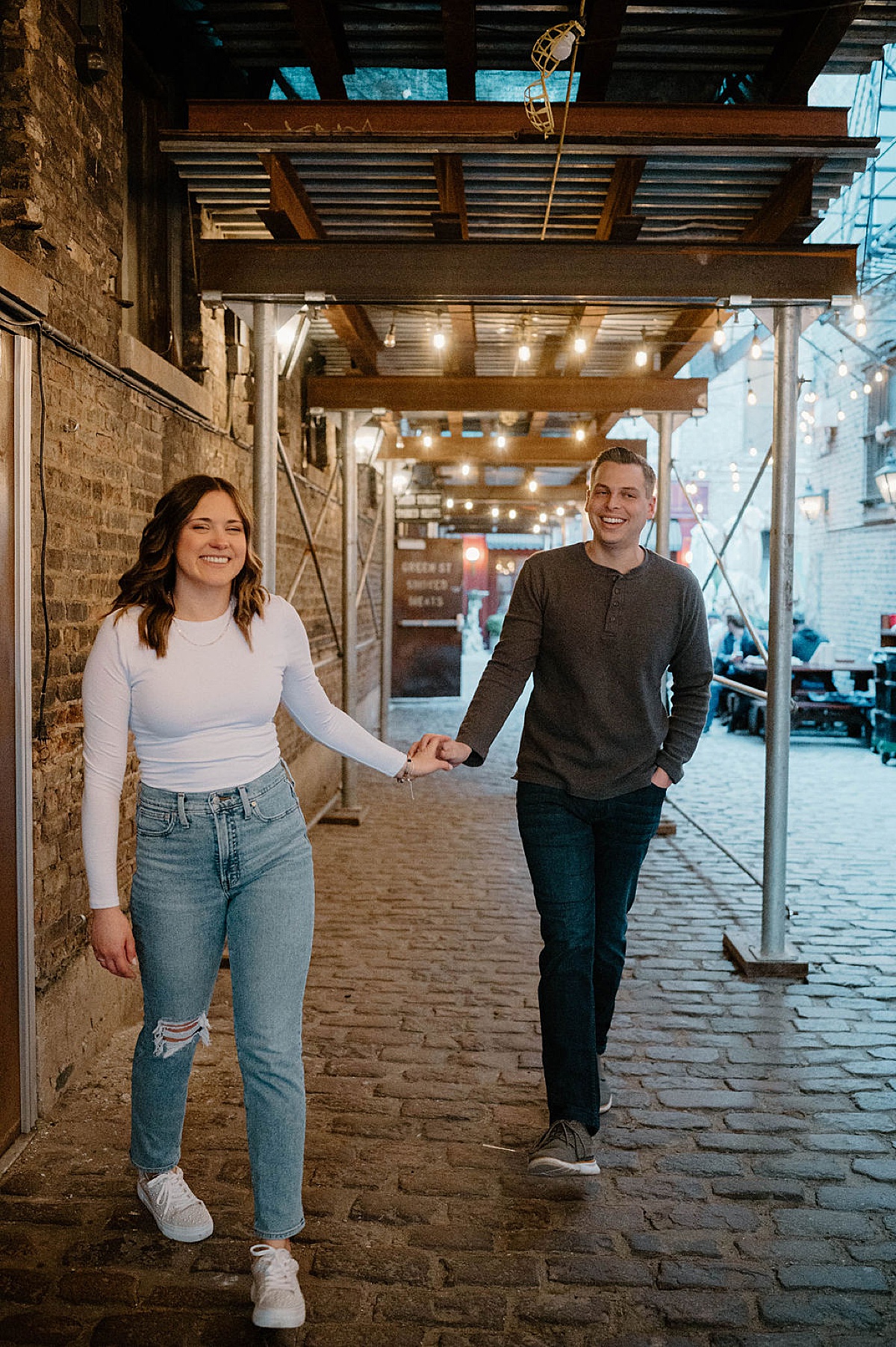 cute couple walk hand in hand during city engagement shoot with chicago wedding photographer
