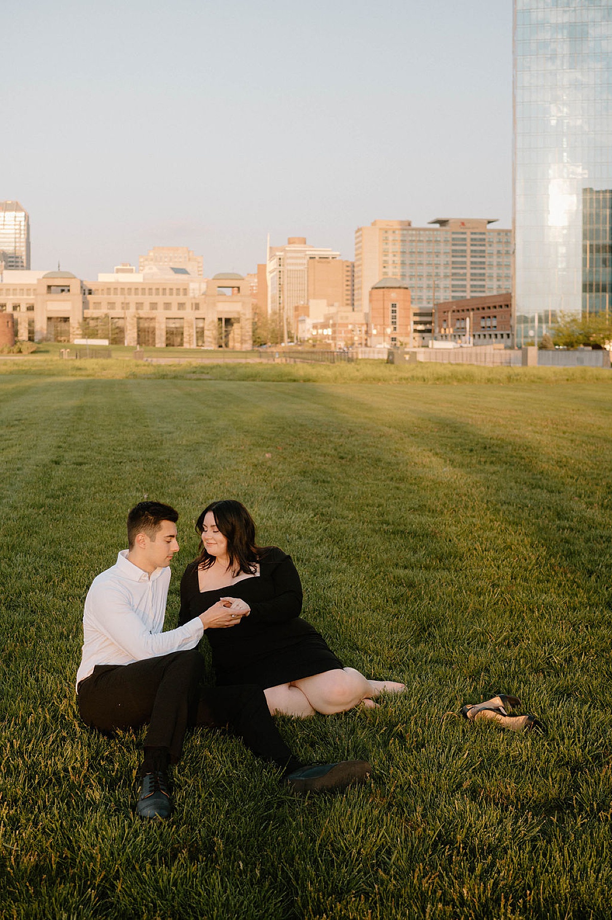 Cute city couple lay in the grass during Indianapolis sunset engagement shoot
