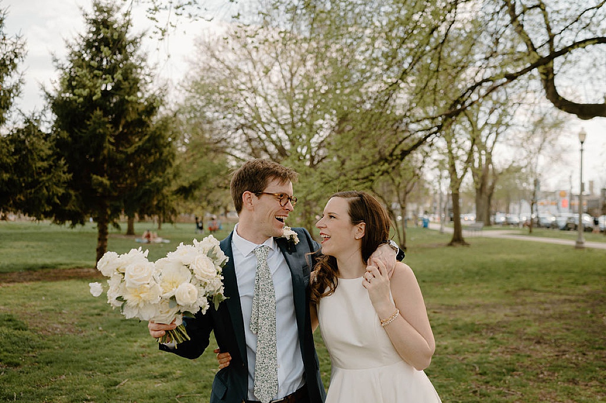 bride and groom with white flowers pose in field during spring wedding at Artifact Events
