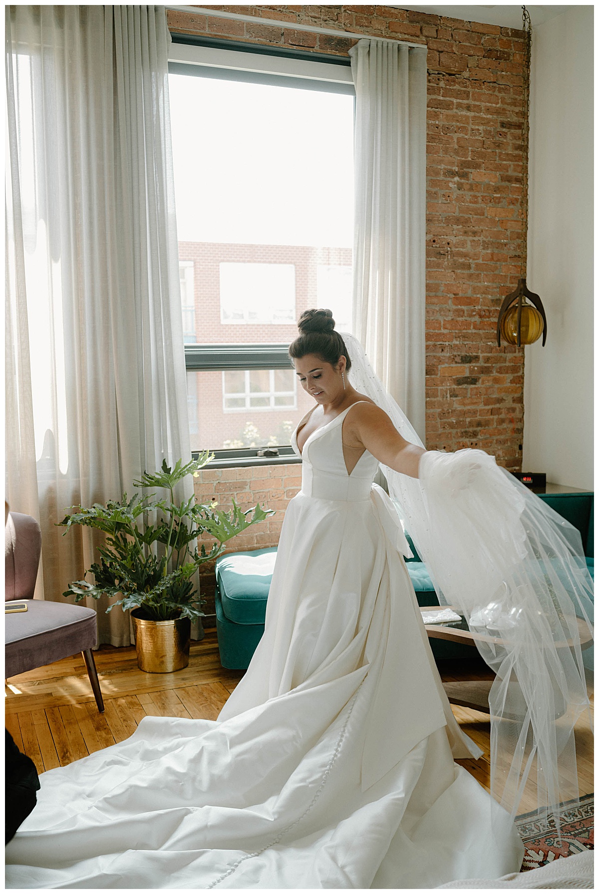 woman holds out veil as she looks at her gown by Chicago photographer