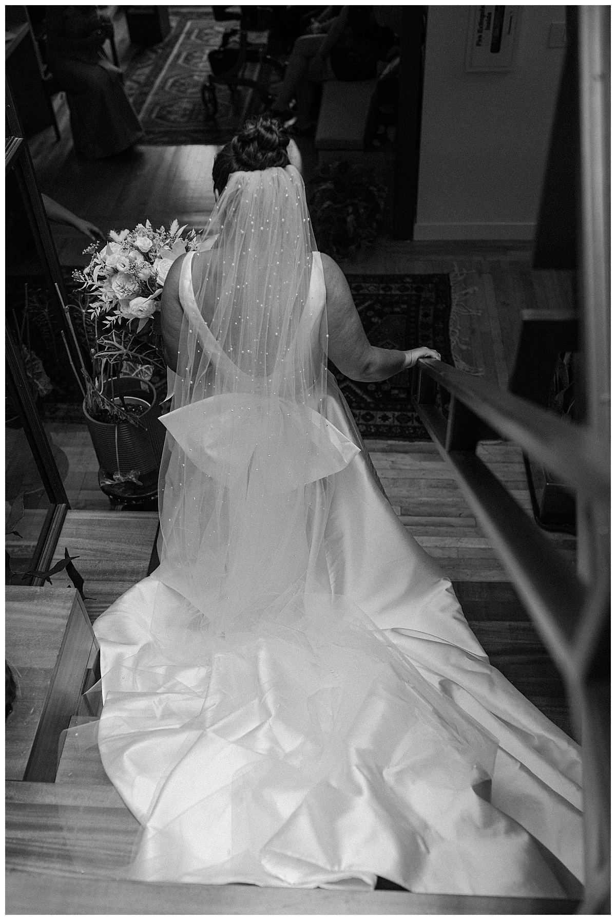 woman walks down stairs in gown holding bouquet by Chicago photographer
