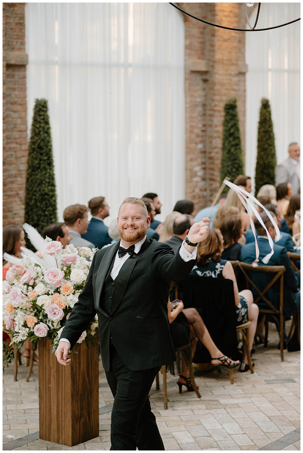 man waves ribbon walking down aisle during ceremony by Chicago photographer