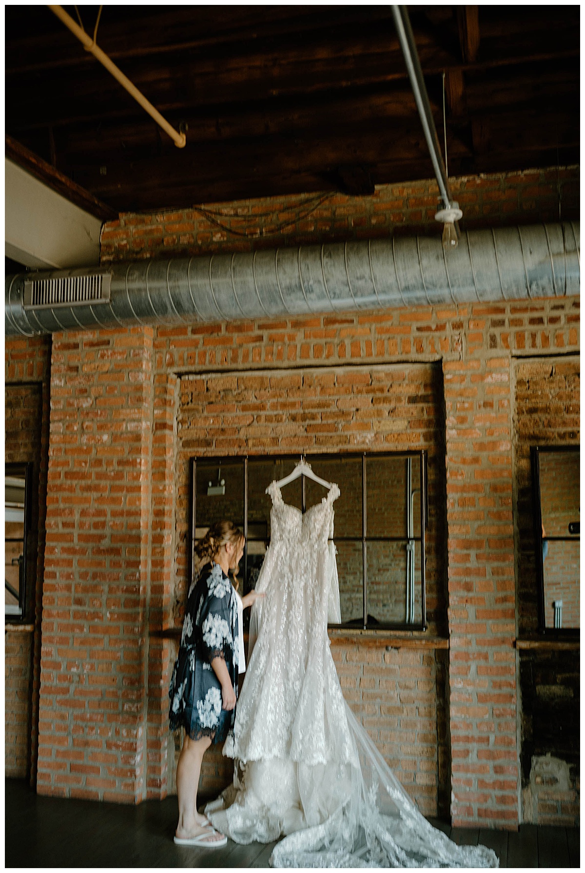 woman admires dress hanging on brick wall at summer Fairlie wedding