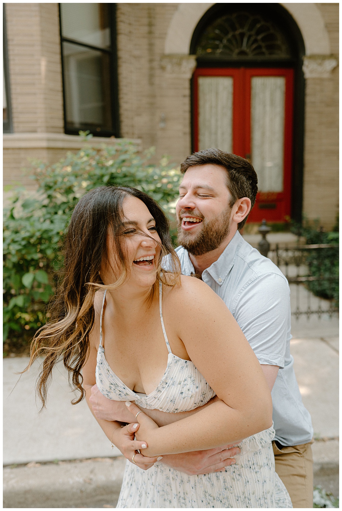 husband to be holds his girl from behind as they laugh by Indigo Lace Collective