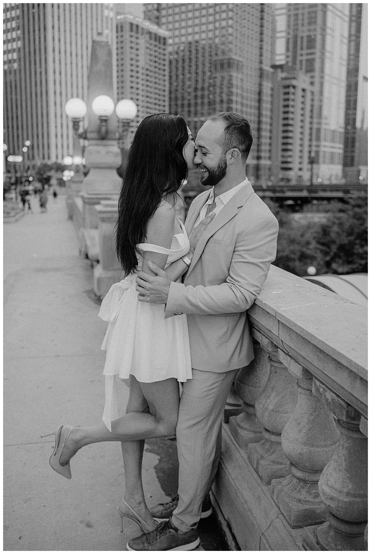 woman leans against man on bridge during downtown engagement session