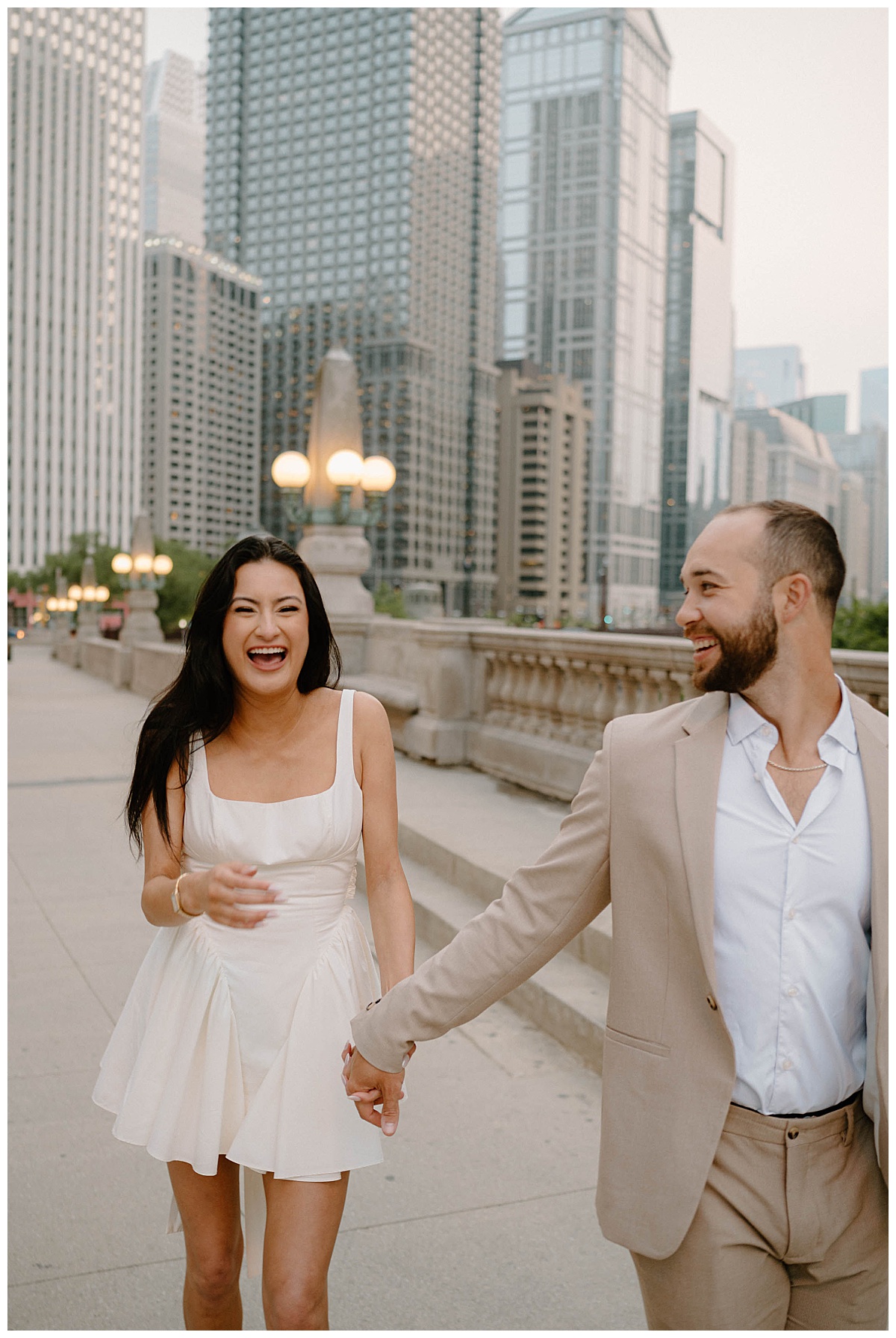 couple laughs together while walking and holding hands during downtown engagement session