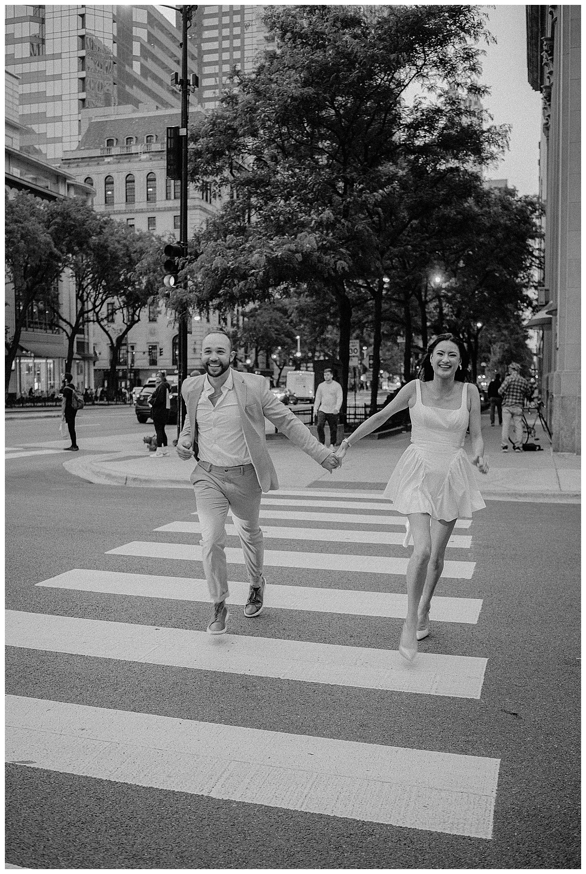 man and woman laugh while running across the street holding hands by Indigo Lace Collective