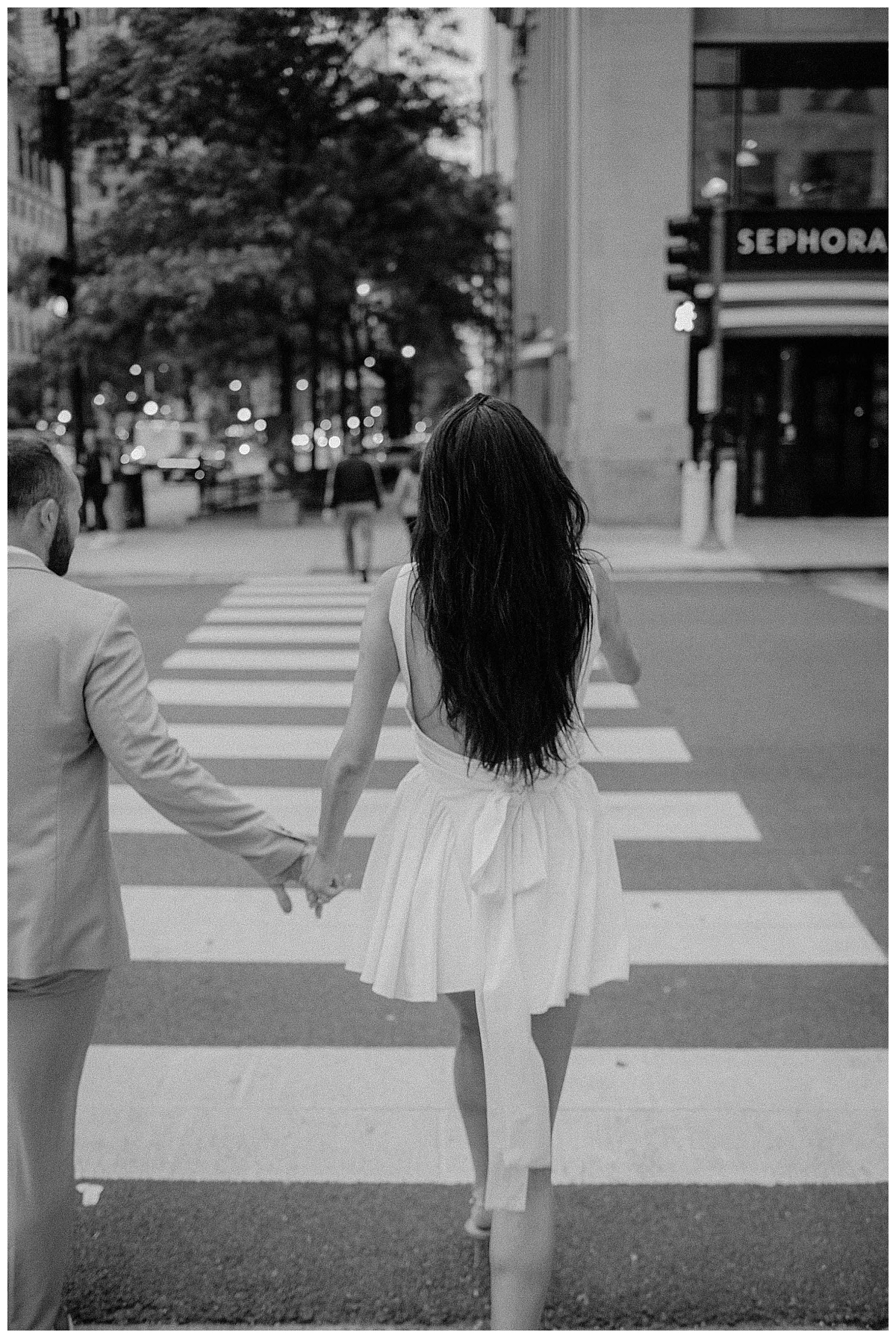 couple crosses street holding hands during downtown engagement session