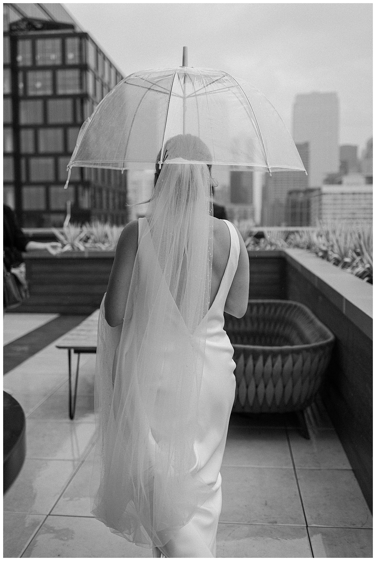 bride holds umbrella over herself on balcony by Midwest wedding photographer