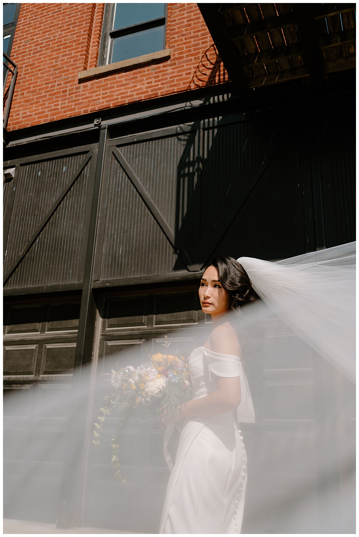 bride's veil blows in the wind as she looks over her shoulder by Chicago wedding photographer