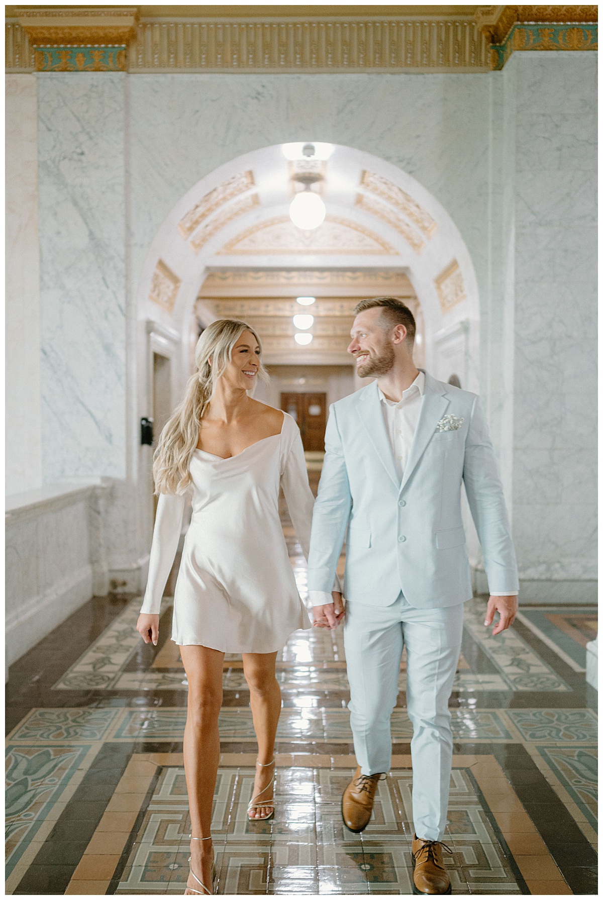 couple walks through halls holding hands and smiling at Downtown Fort Wayne Courthouse Elopement