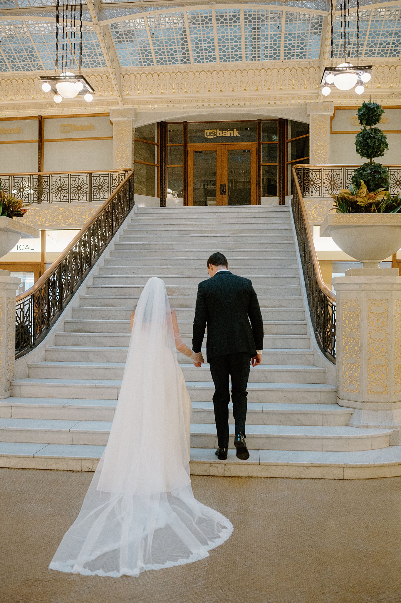 couple holds hands walking up stairs to Galleria Marchetti Reception