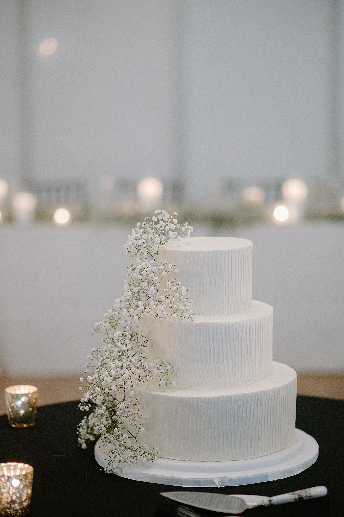simple wedding cake decorated with baby's breath sits on table at Galleria Marchetti Reception