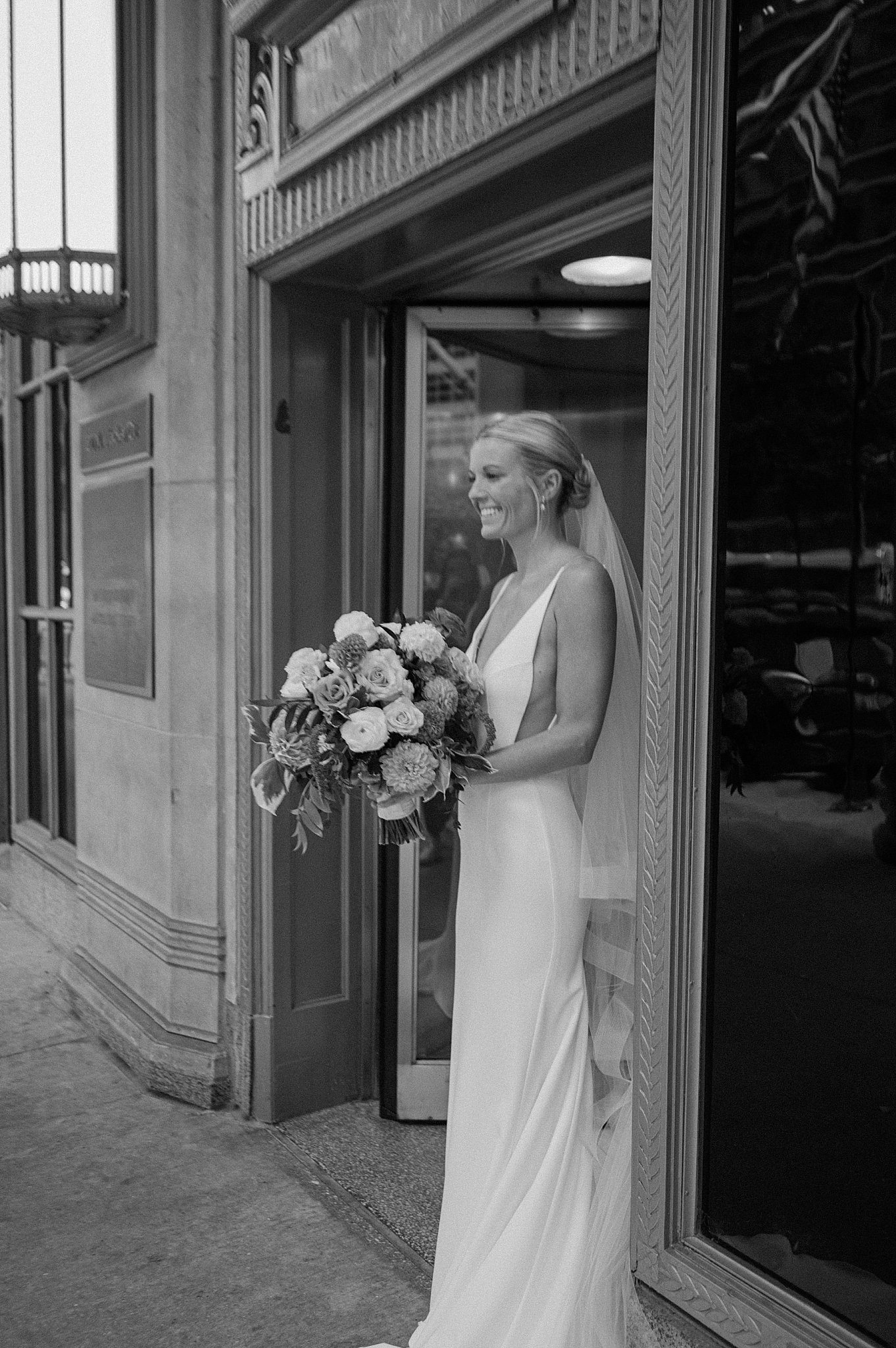 bride grins as she holds her bouquet at Cafe Brauer