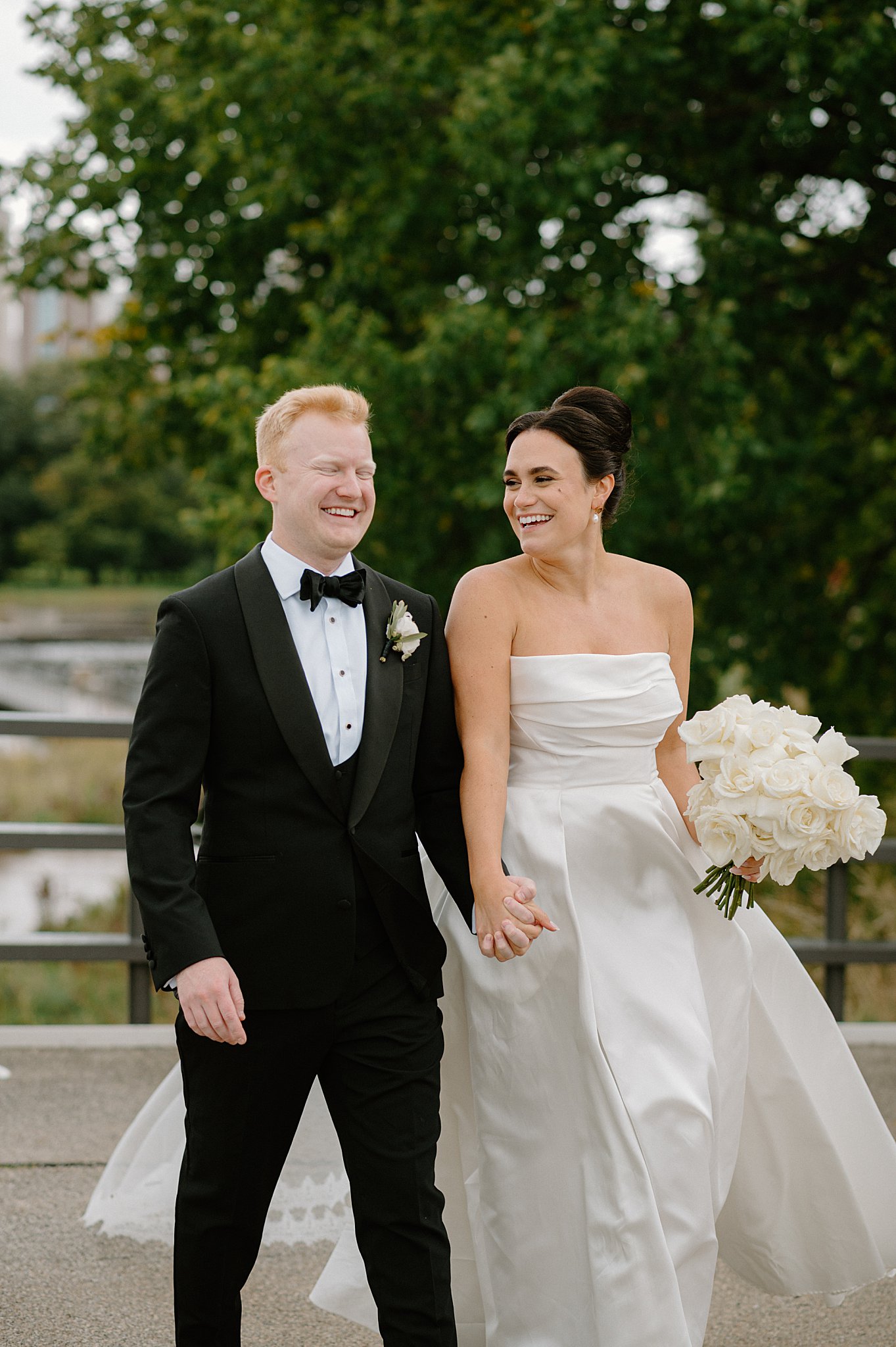 couple laughs as they hold hands by Midwest wedding photographer