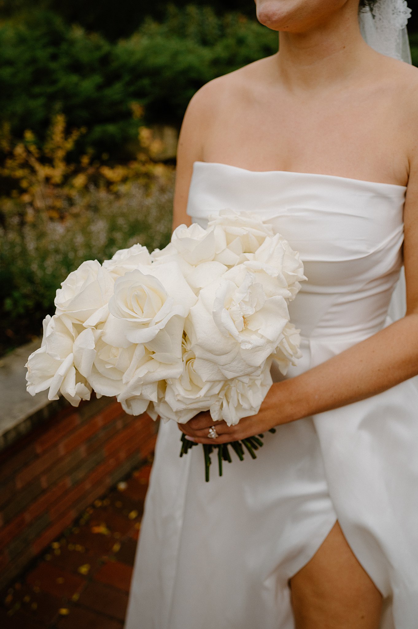 bride holds bouquet of white roses by Indigo Lace Collective