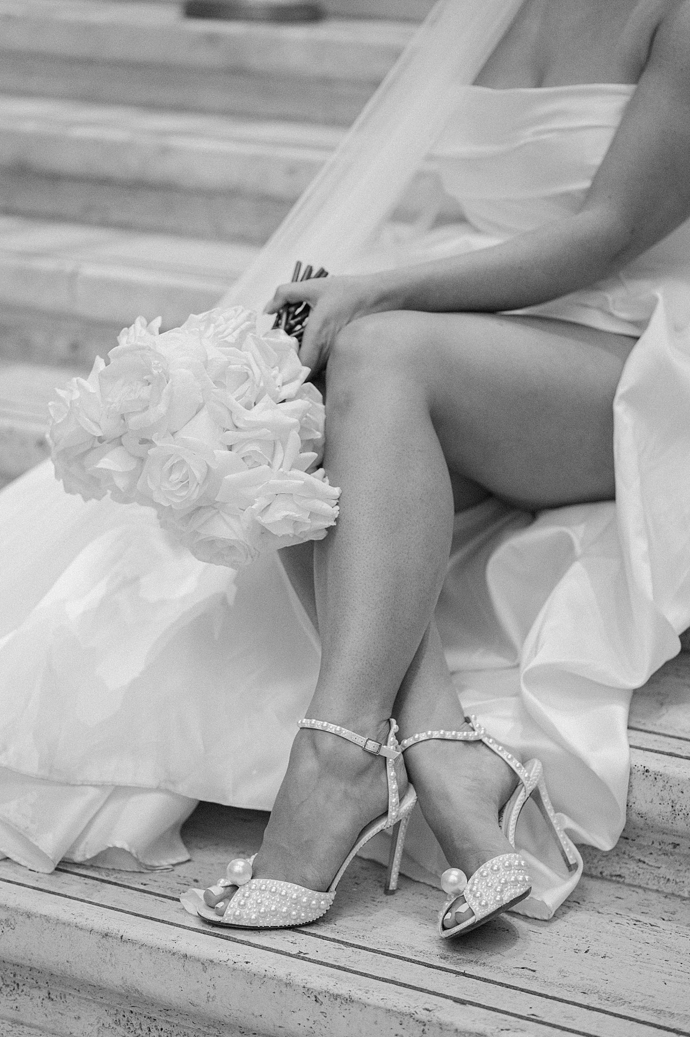 bride sits on stairs with ankles crossed and slit in dress showing off her legs by Indigo Lace Collective