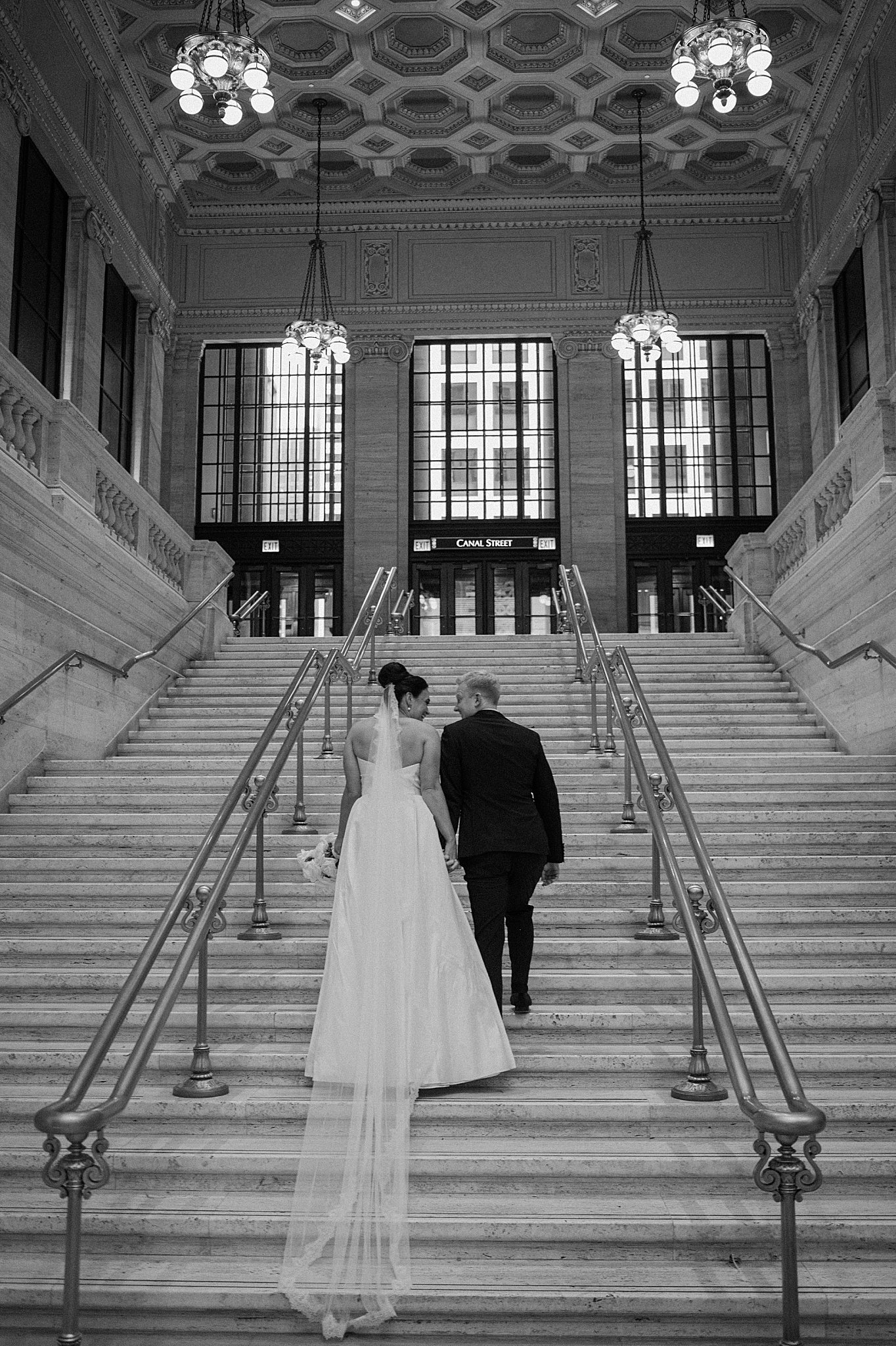 newlyweds hold hands as they climb stairs after their downtown Chicago ceremony
