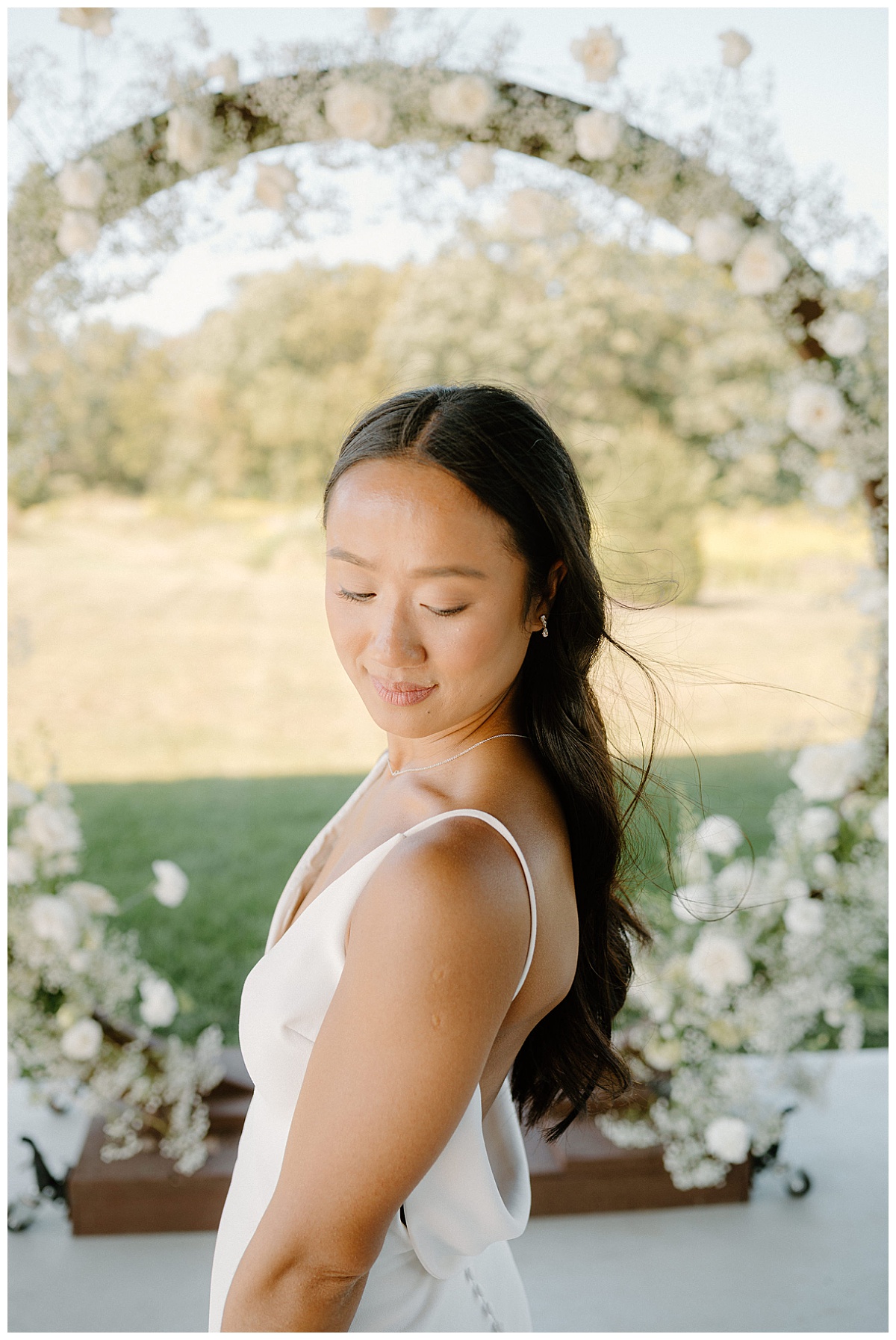 bride looks over shoulder as hair blows in wind by Midwest wedding photographer